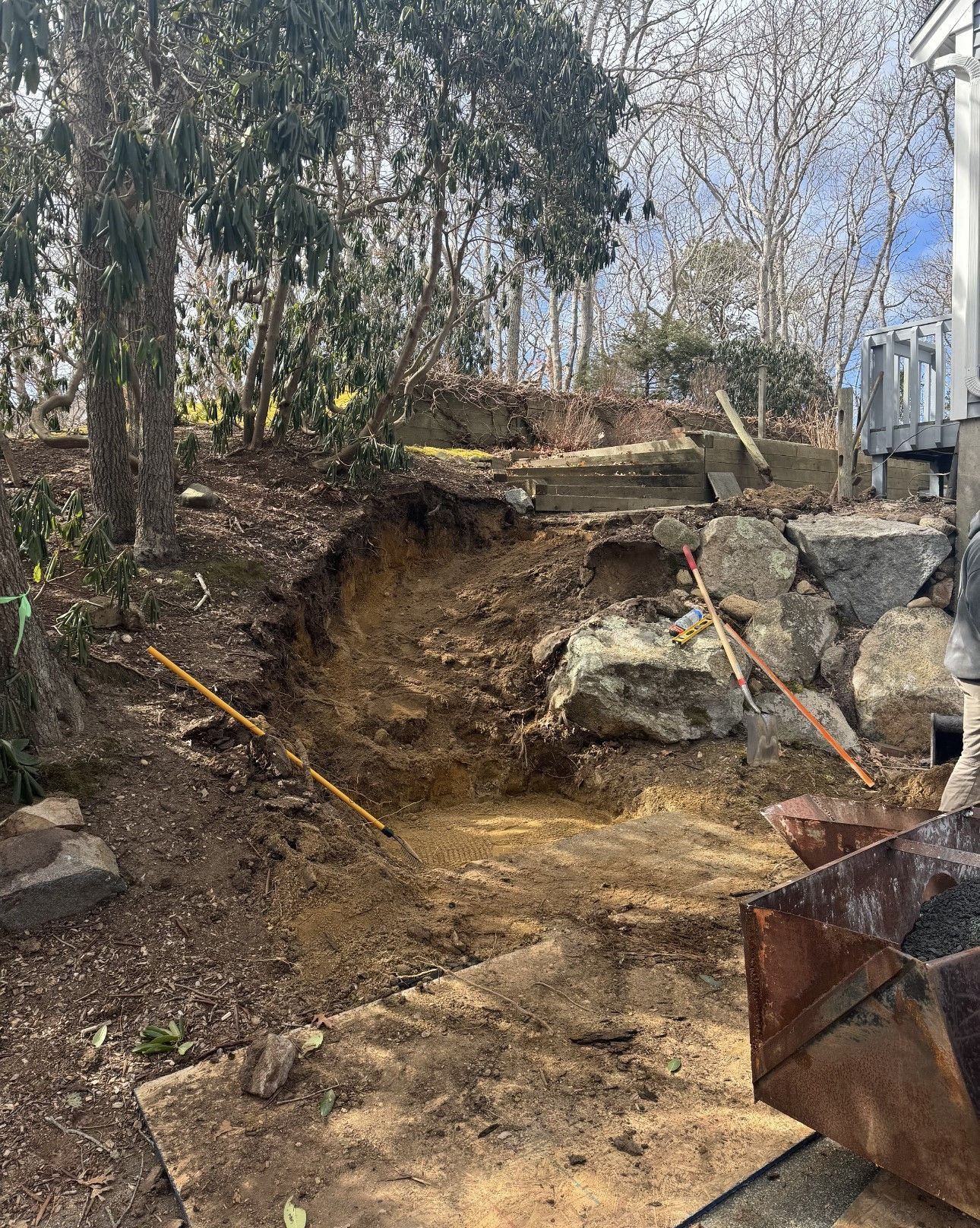 A large hole in the ground is being filled with dirt and rocks.