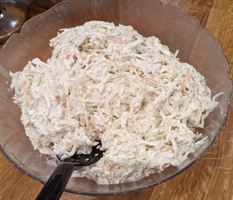 A bowl of coleslaw with a spoon in it