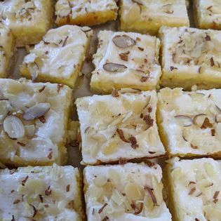 A bunch of squares of cake with almonds on top