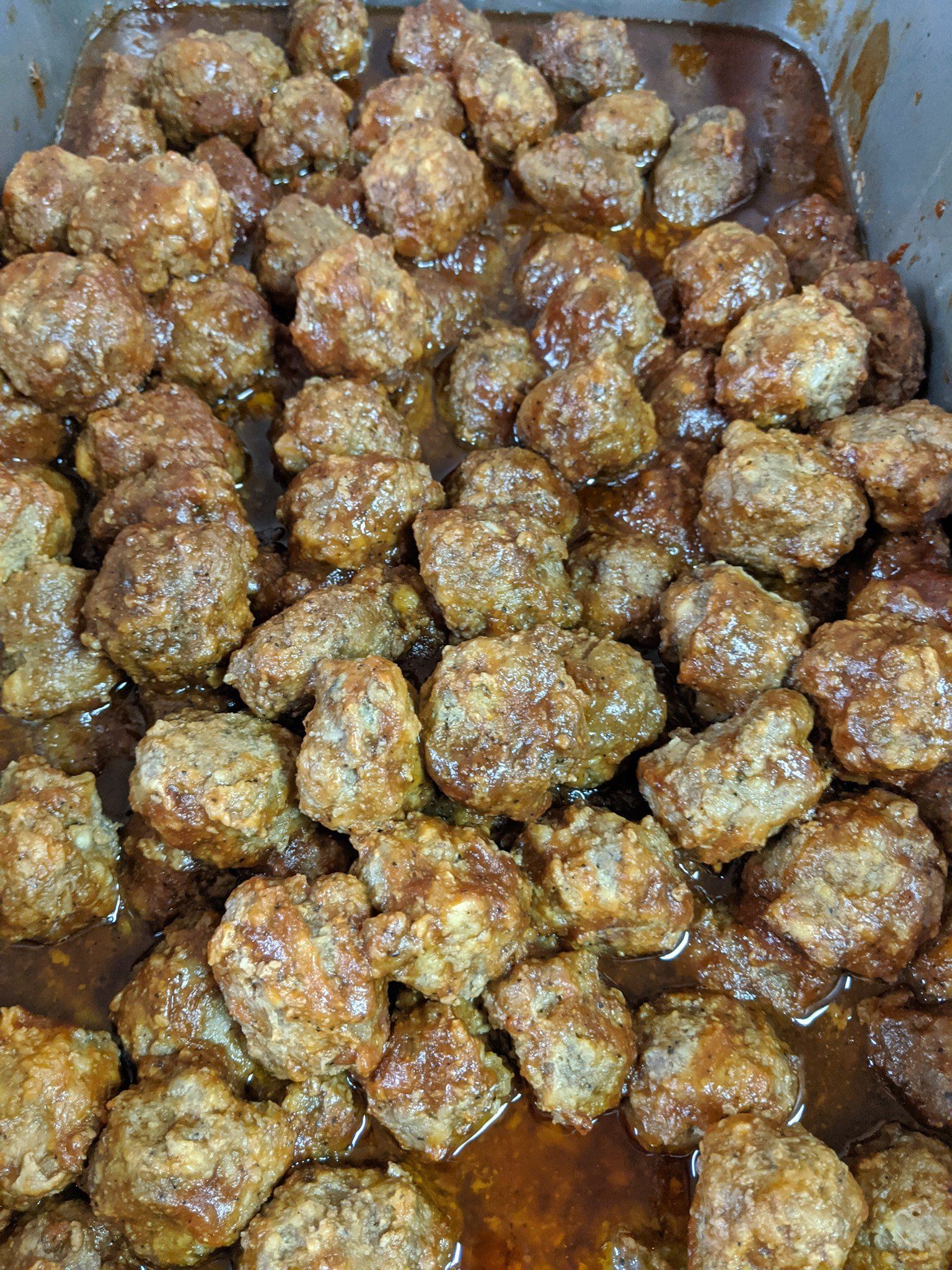 A pile of meatballs in a sauce in a pan.