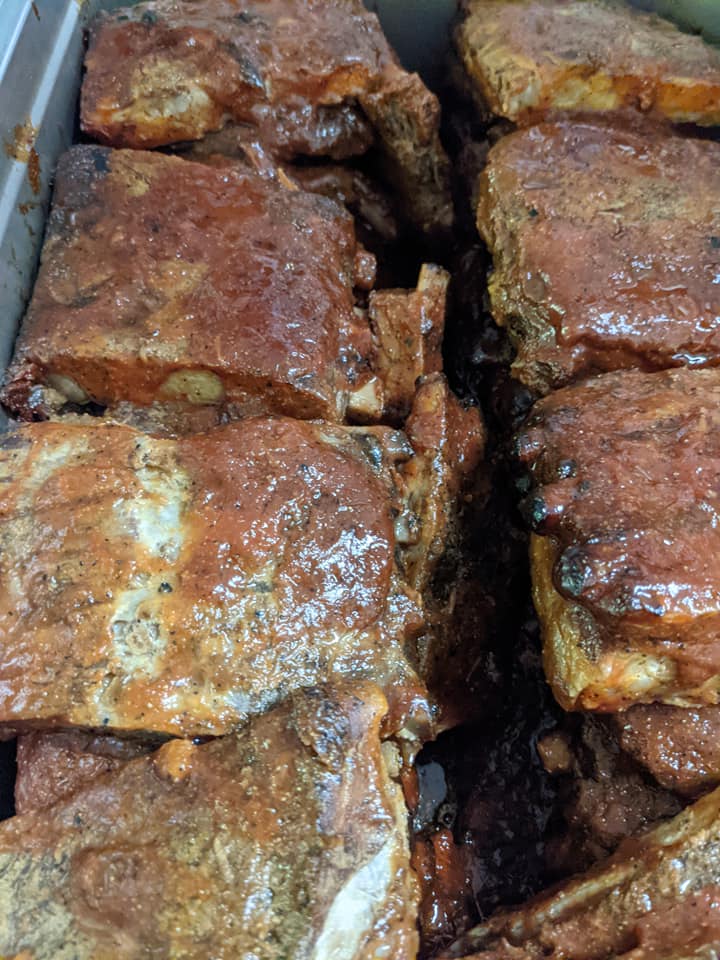 A close up of a tray of meat with sauce on it.