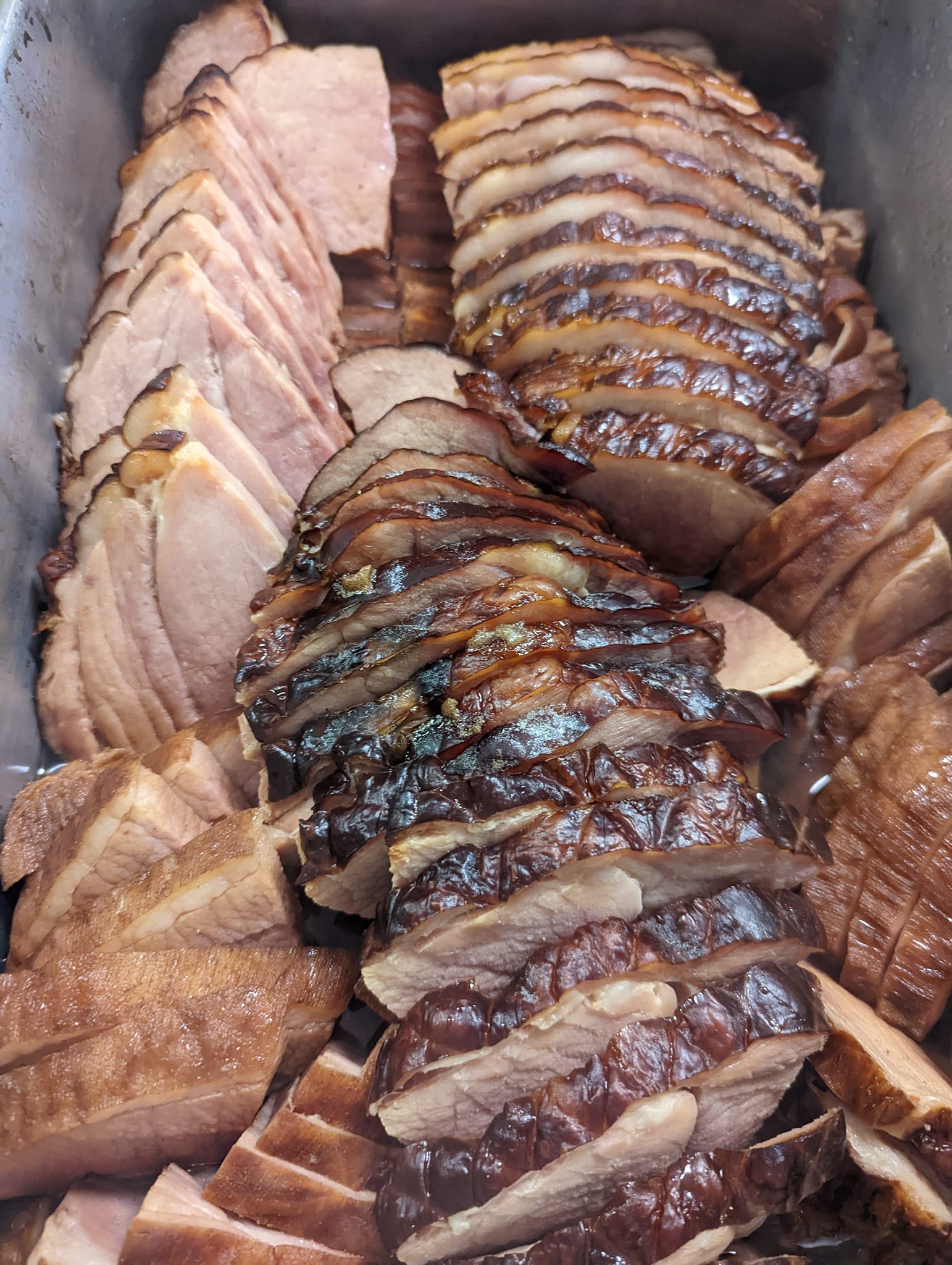 A tray of sliced ham is sitting on a table.
