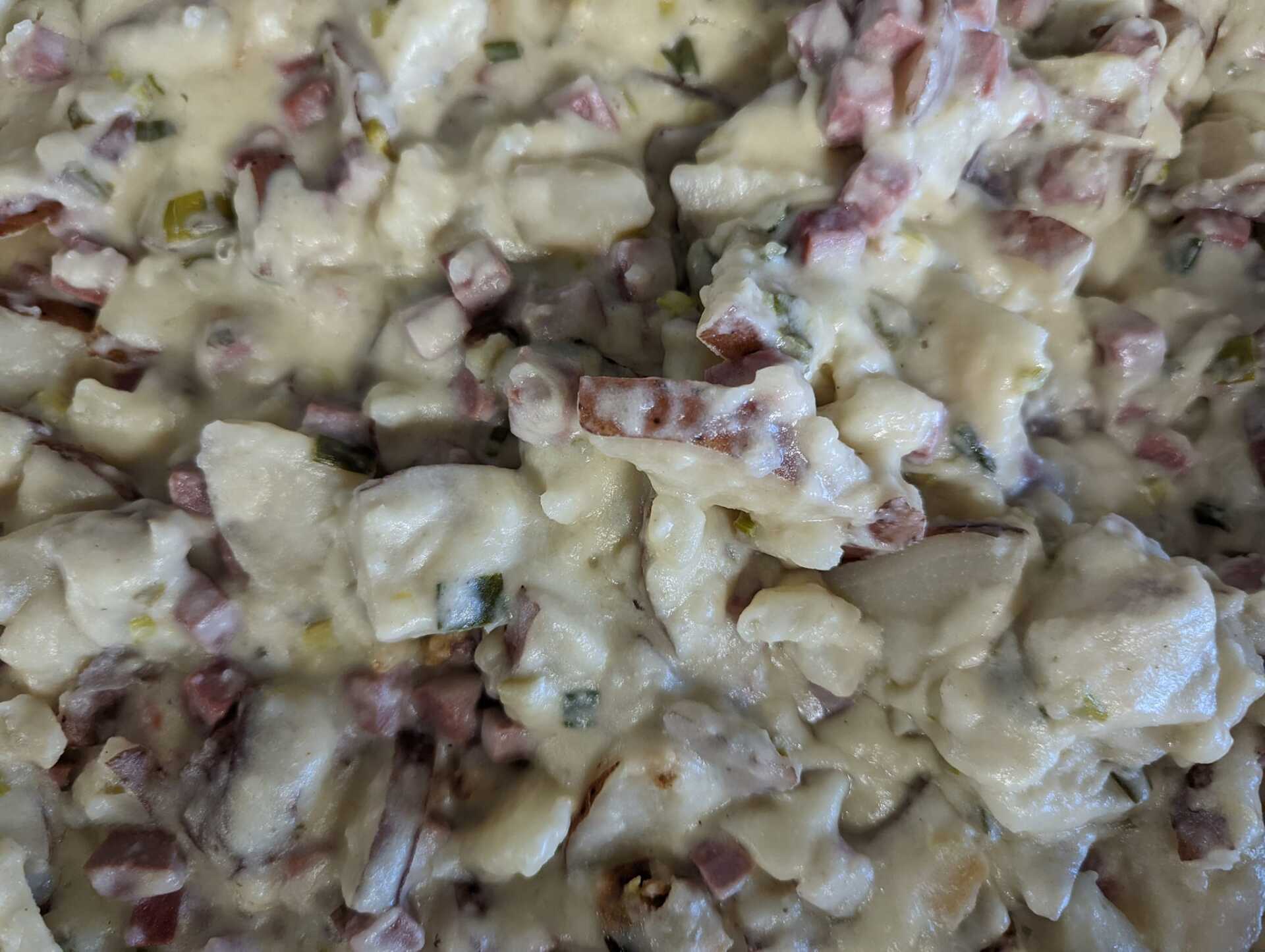 A close up of a pasta salad with bacon and cheese.
