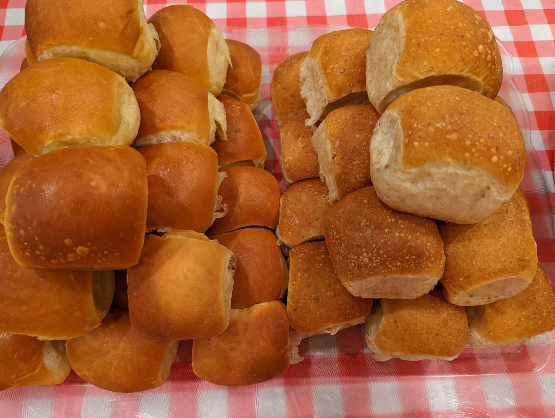 A tray of rolls and buns on a checkered table cloth.