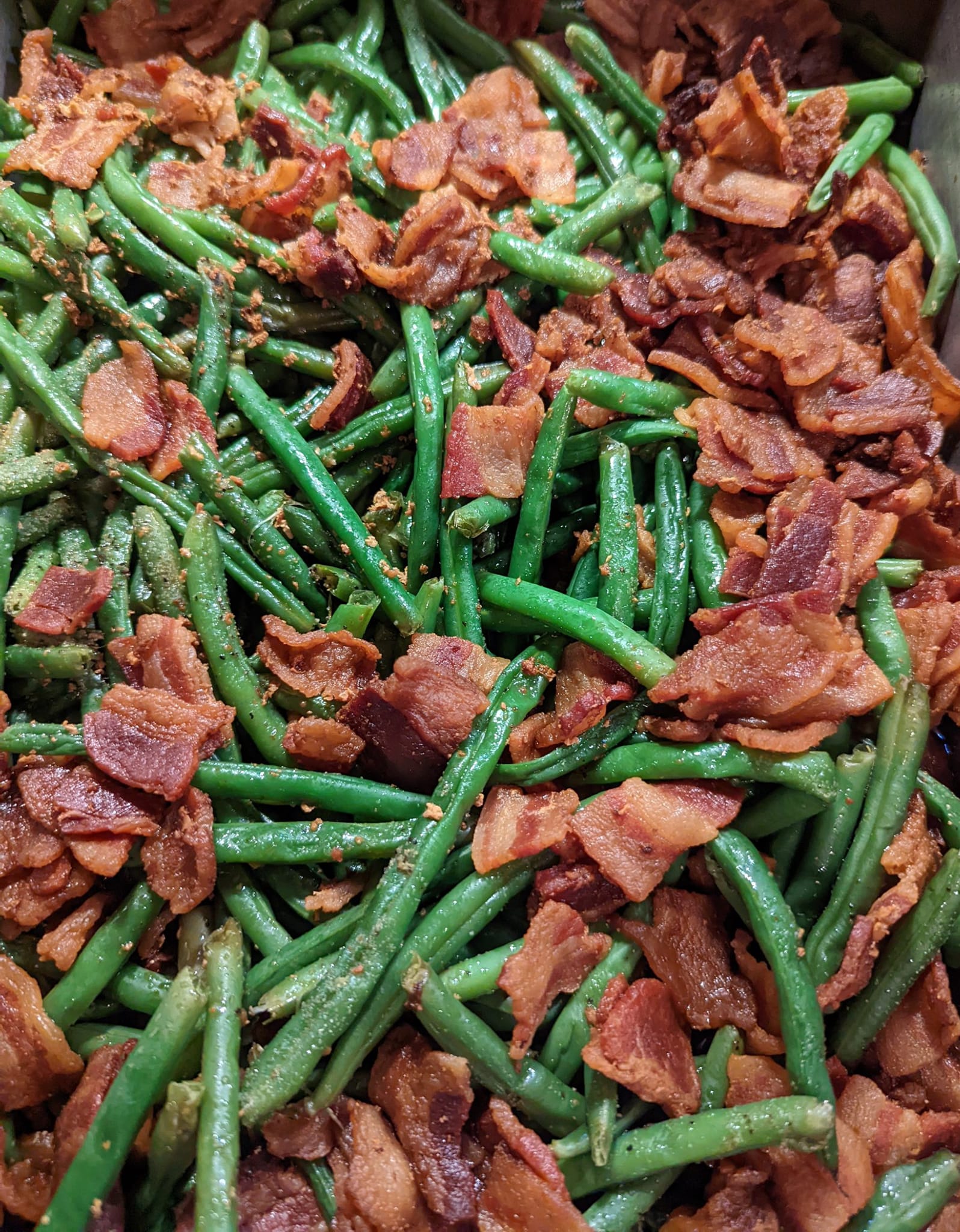 A close up of green beans with bacon in a bowl.
