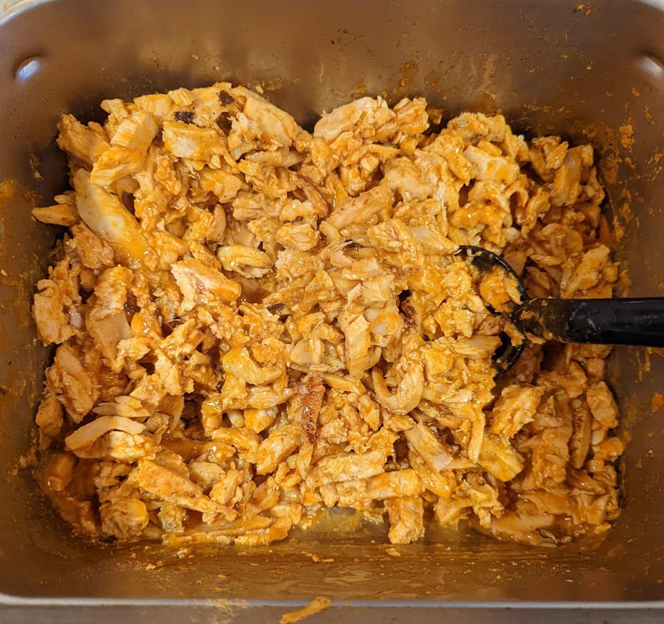 A pan of shredded chicken with a spatula in it