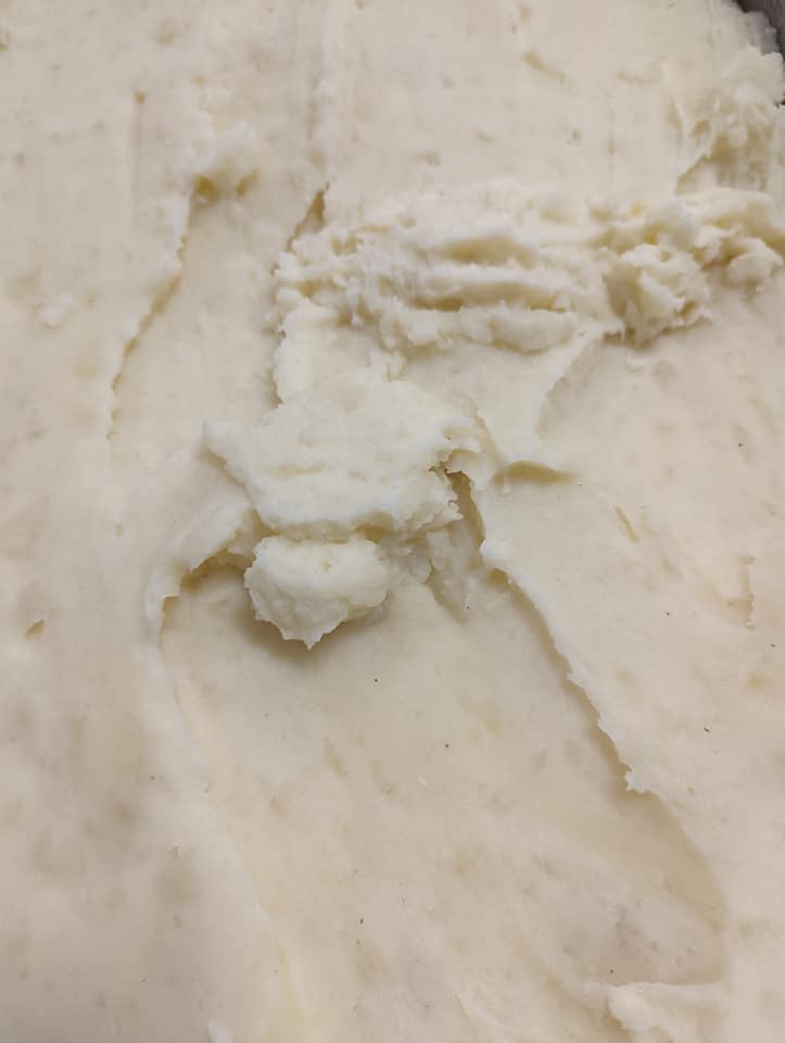 A close up of mashed potatoes in a bowl on a table.