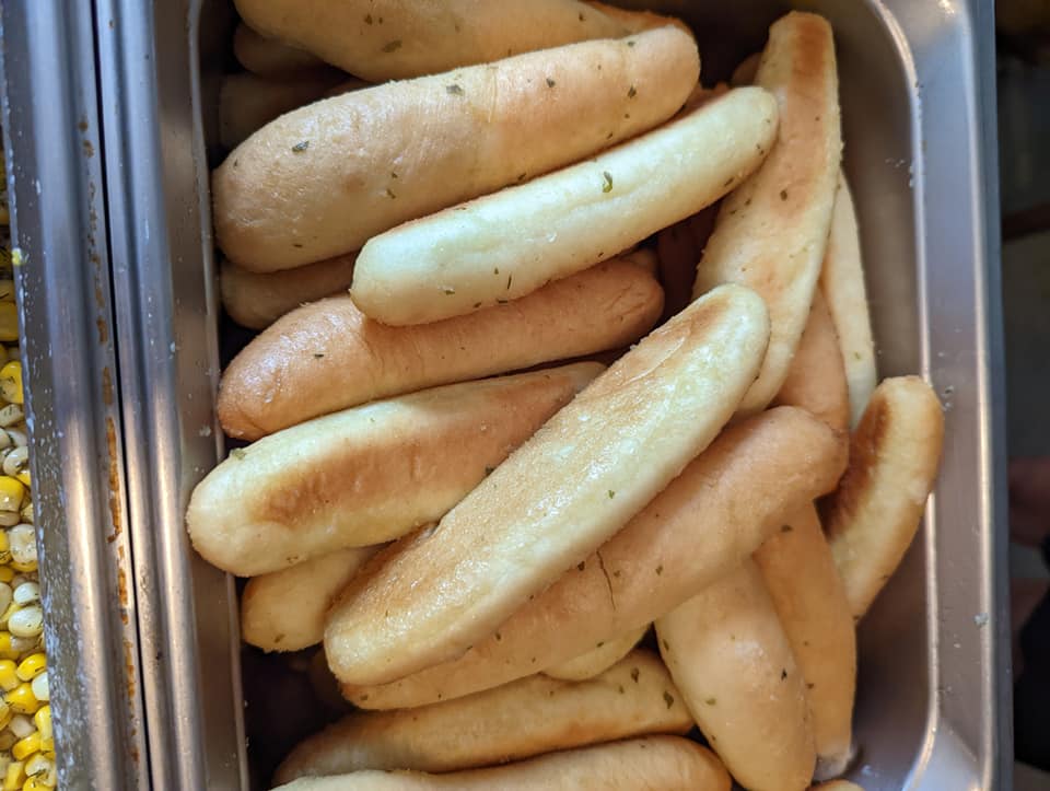 A bunch of hot dogs are sitting in a metal pan.
