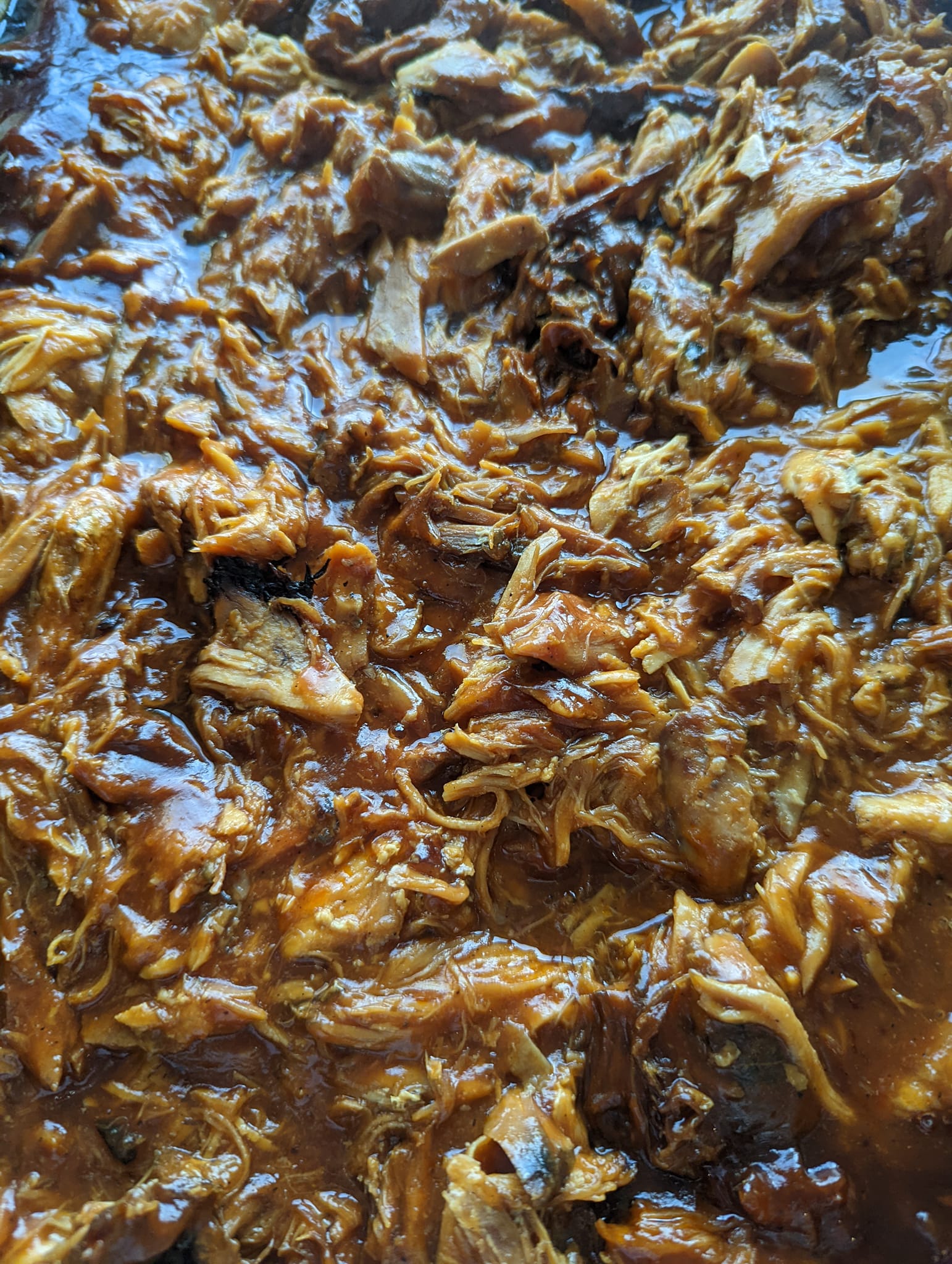 A close up of a casserole dish filled with pulled pork and sauce.