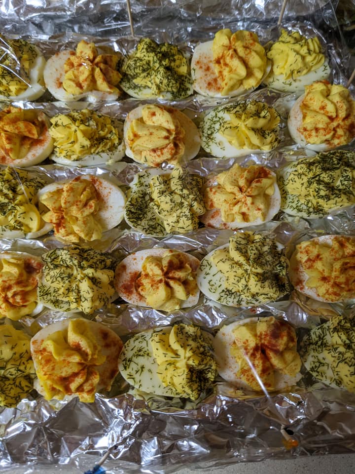 A bunch of stuffed eggs are sitting on top of a tin foil tray.