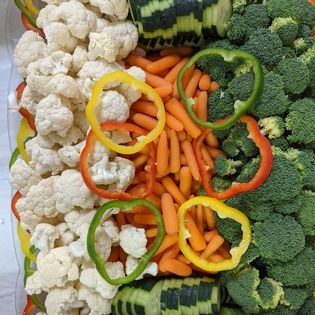 A tray of vegetables including broccoli , cauliflower , carrots , peppers and cucumbers.