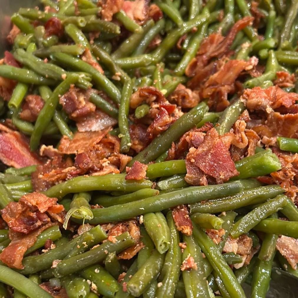 A close up of green beans with bacon in a bowl.