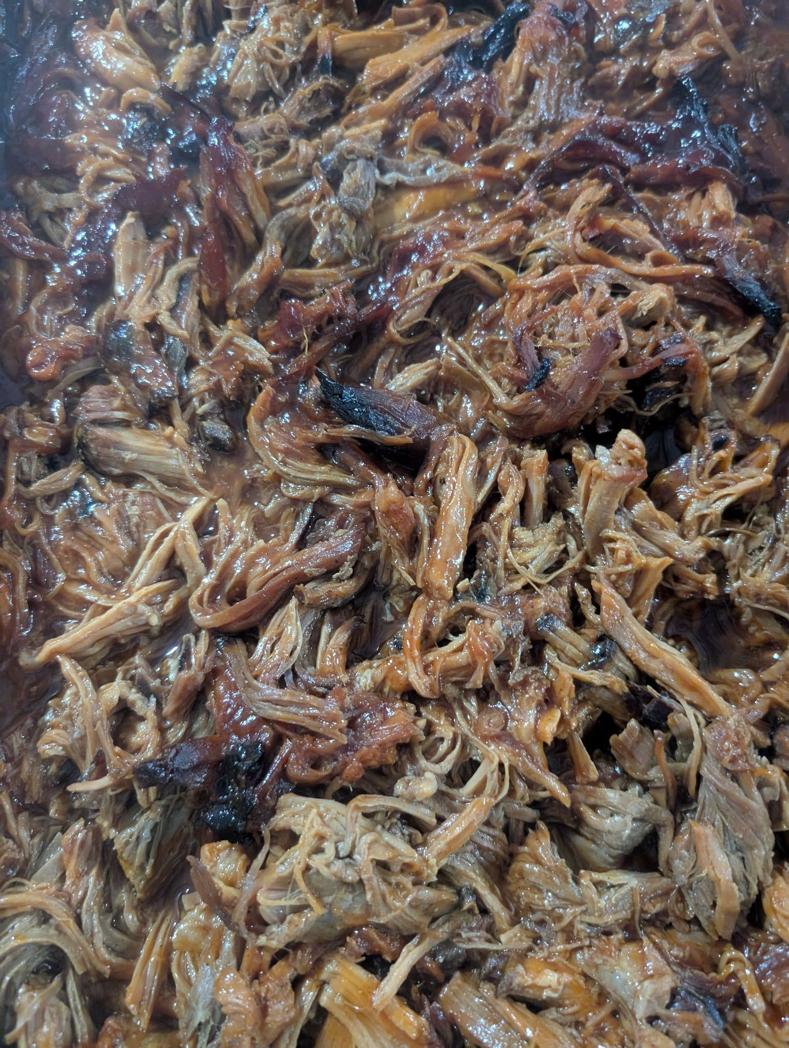 A close up of a pile of pulled pork in a pan.