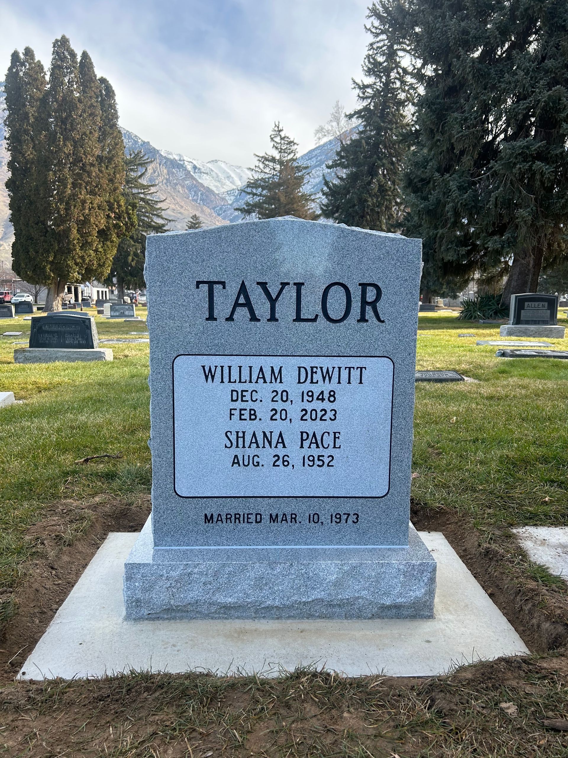 Gray Taylor headstone in a cemetery, listing the names William DeWitt Taylor, dates 1840-1952. Mountain in background.