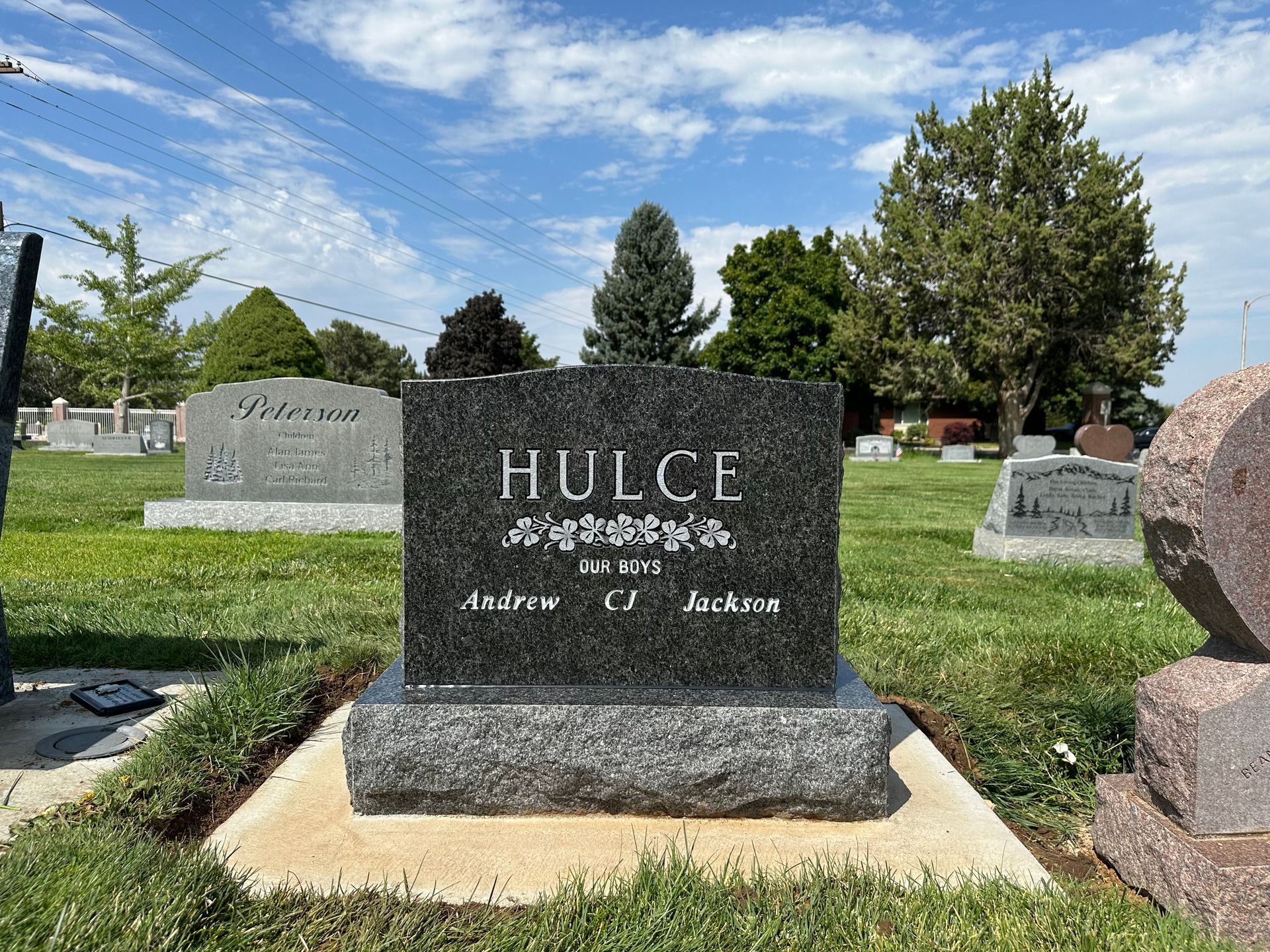Black granite headstone in a cemetery, inscribed with HULCE.