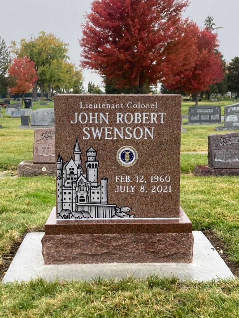 Headstone for Lieutenant Colonel John Robert Swenson, brown with a castle design, red-brown base, in a cemetery.