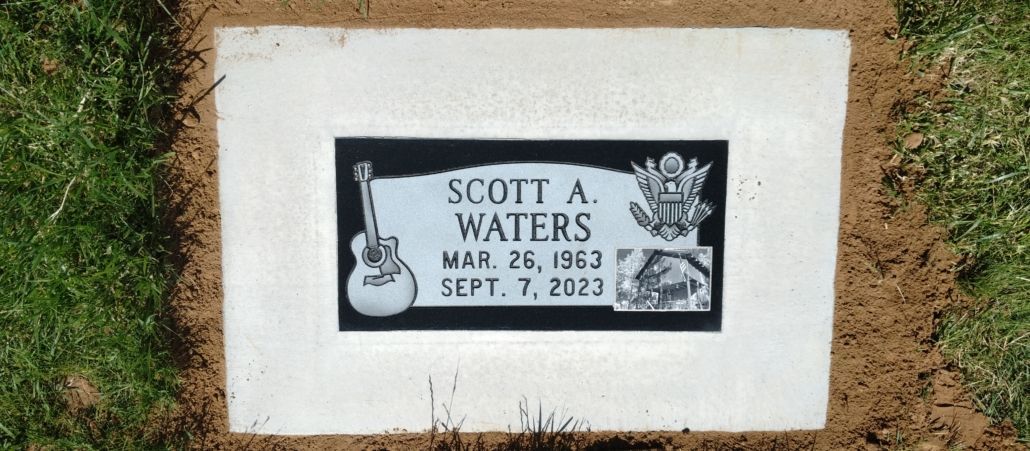 Gravestone for Scott A. Waters. Born March 26, 1963, died Sept. 7, 2023. Features a guitar and emblem.