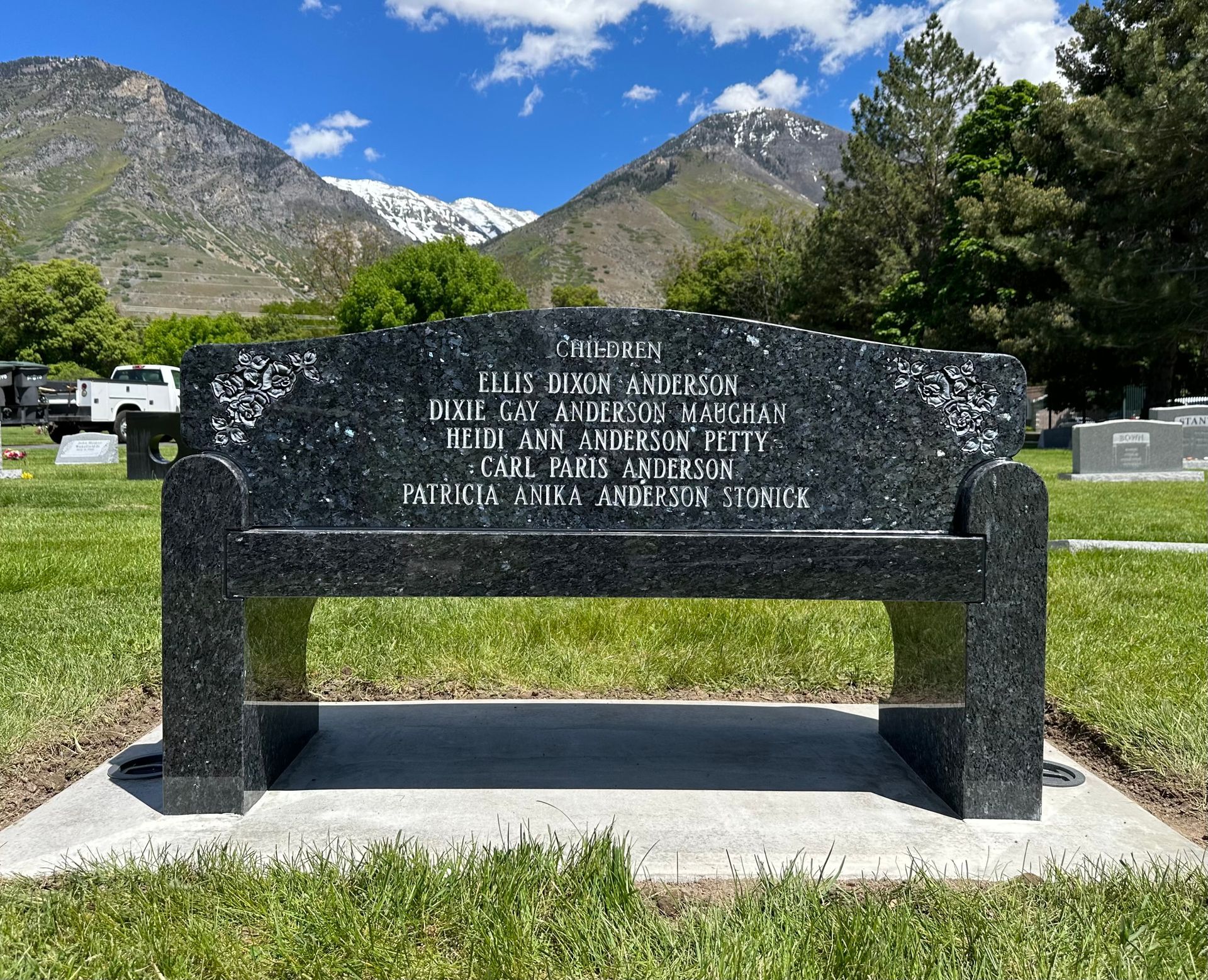 Granite bench in a cemetery with mountains in the background. Inscribed with names.