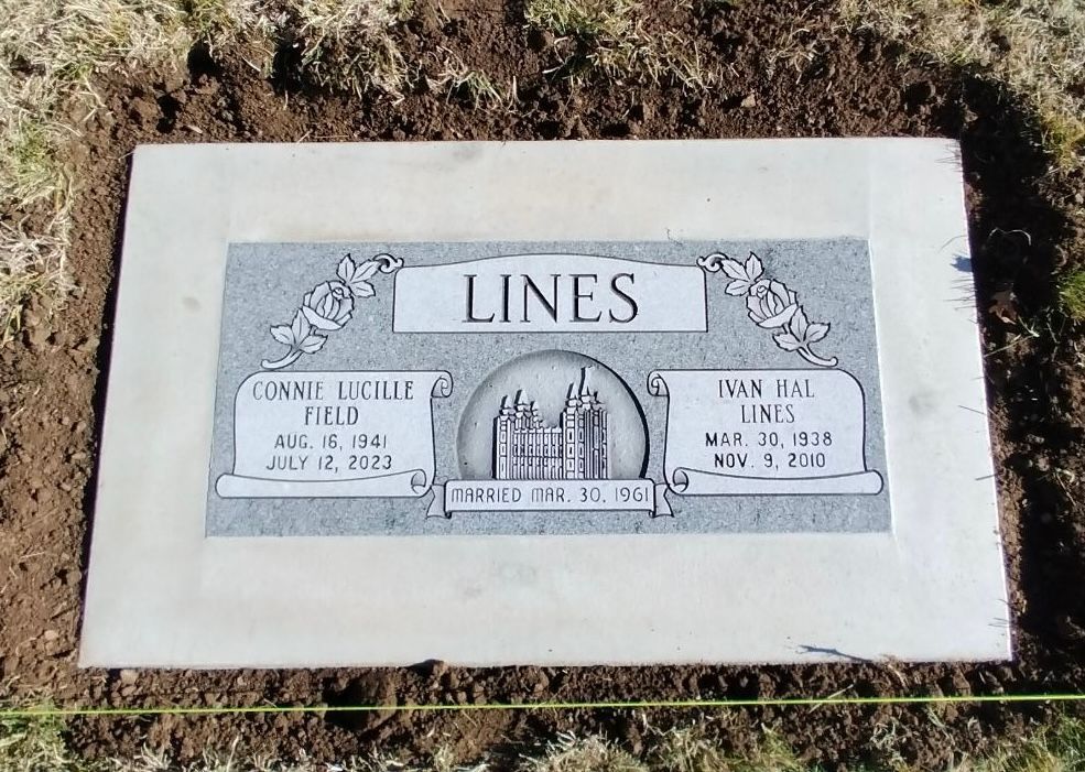 Headstone for the Lines family with names, dates, and an image of city buildings, set in a new grave.