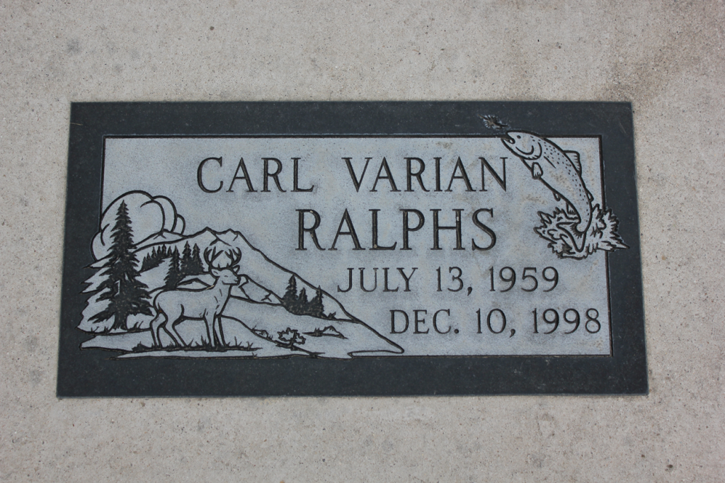 Tombstone of Carl Varian Ralphs: Name, dates (1959-1998), with etched mountains, deer, fish, and trees.