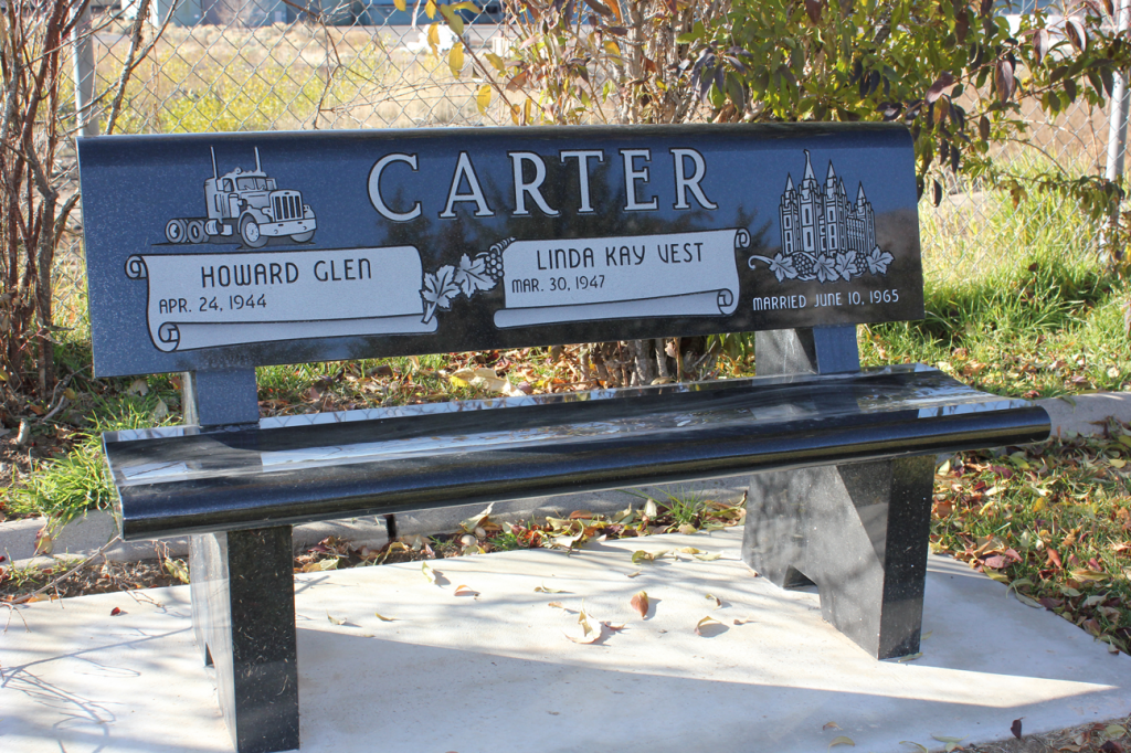 Memorial bench for Carter family with truck and trees carvings; blue and black.