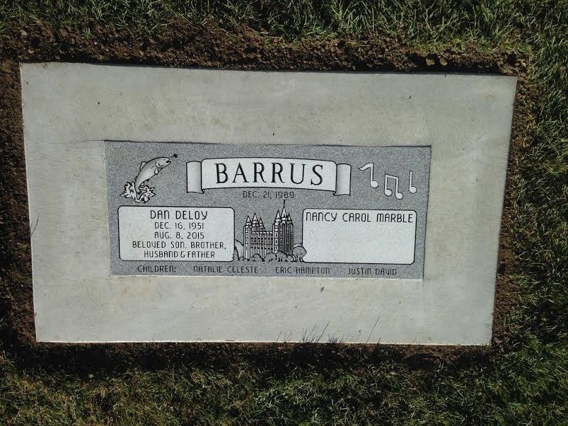 Grave marker with the name BARRUS. Includes dates, and symbols like a dolphin and music notes.