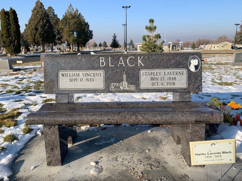 Grave bench with the surname BLACK, two plaques with names and dates in a snowy cemetery.