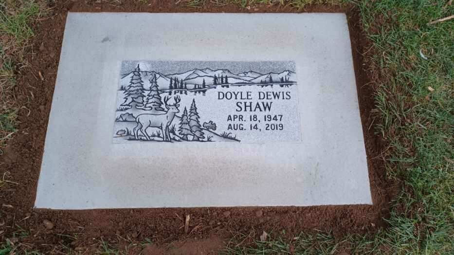 Gravestone of Doyle Dewis Shaw with etched landscape.