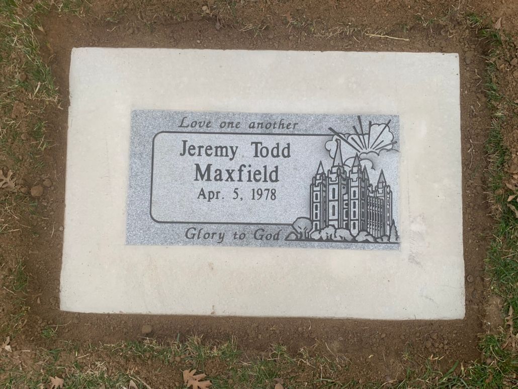 Grave marker for Jeremy Todd Maxfield, including his name, birth date, and a depiction of a building.