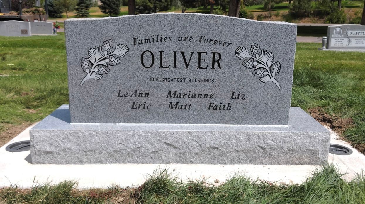 Gray granite headstone in a cemetery with the name 