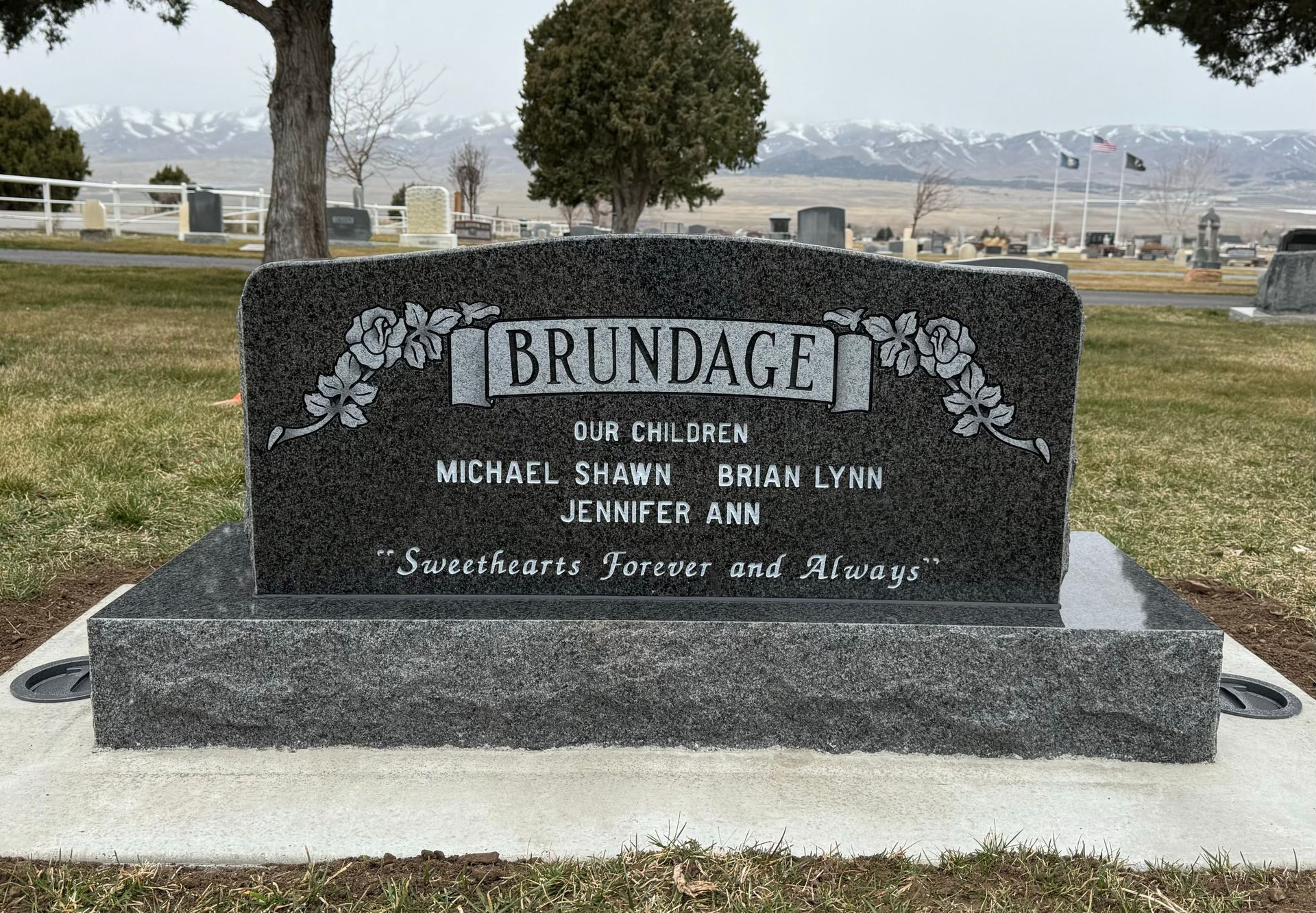 Grave marker with the last name BRUNDAGE, listing names of children: Michael, Brian, and Jennifer. In a cemetery.