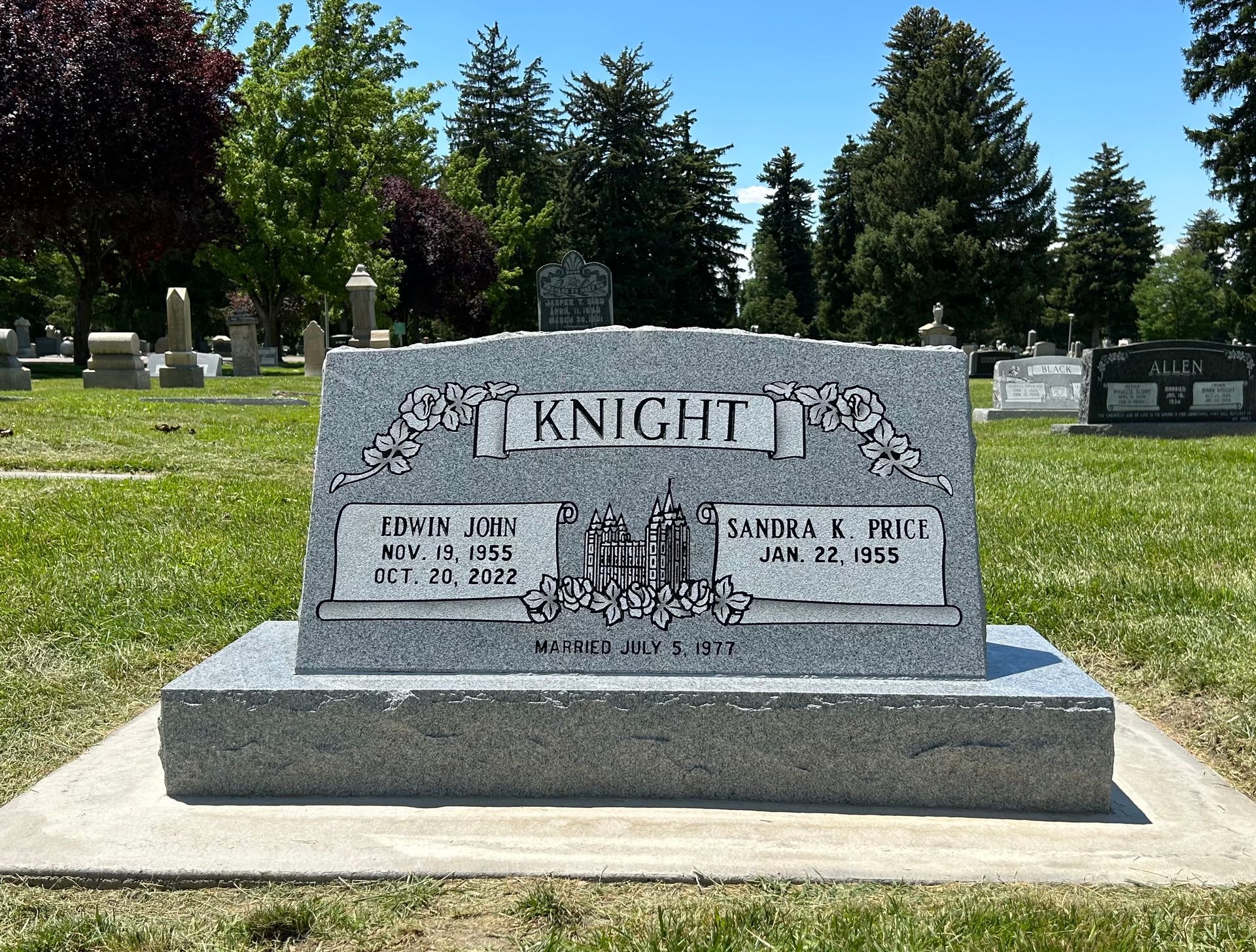 Gray headstone in a cemetery. The headstone reads 