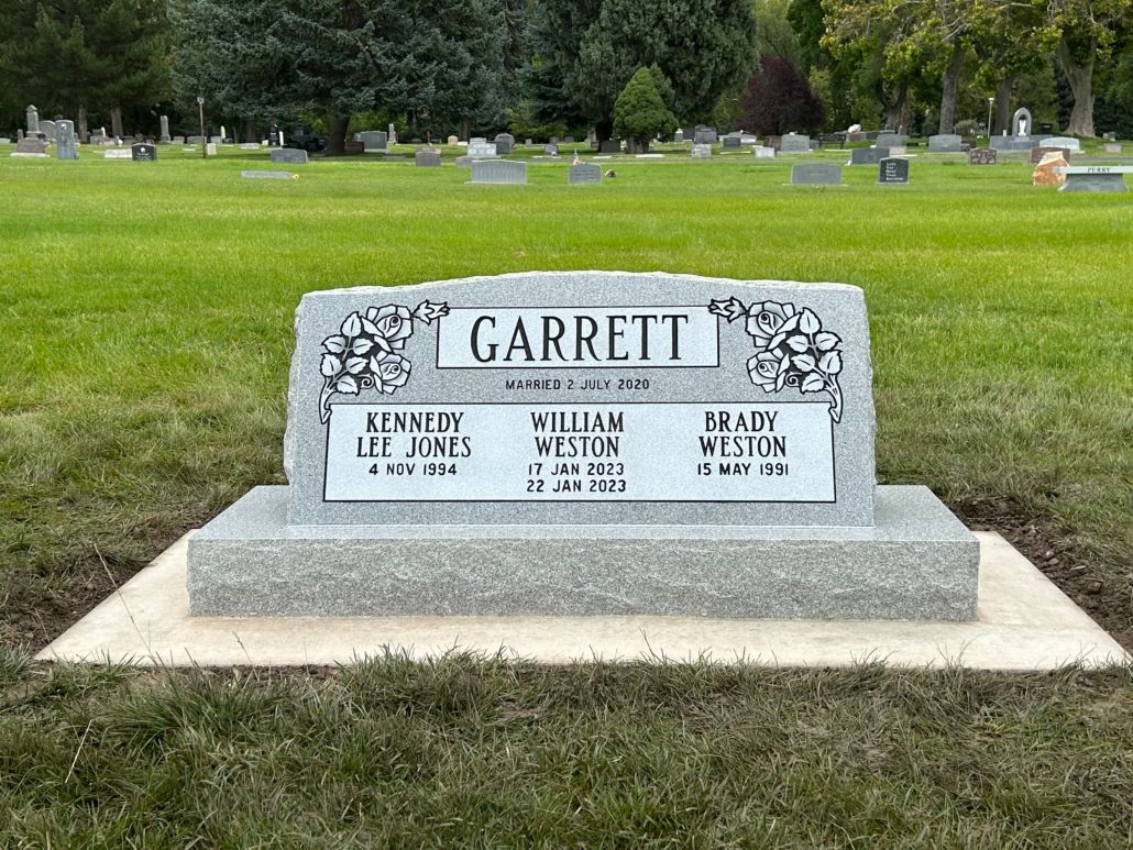 Gray granite headstone in a cemetery; names include Garrett, Kenneth, William, and Henry.