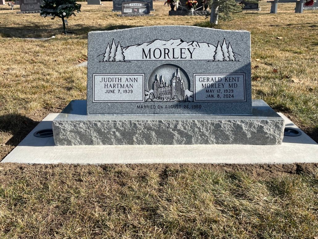 A gray gravestone in a grassy cemetery with the family name 
