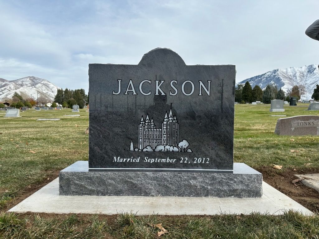 Gray granite Jackson family headstone with a castle etching, set in a cemetery.