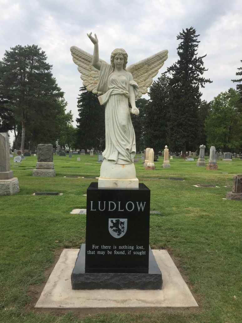 White angel statue on a black gravestone in a cemetery