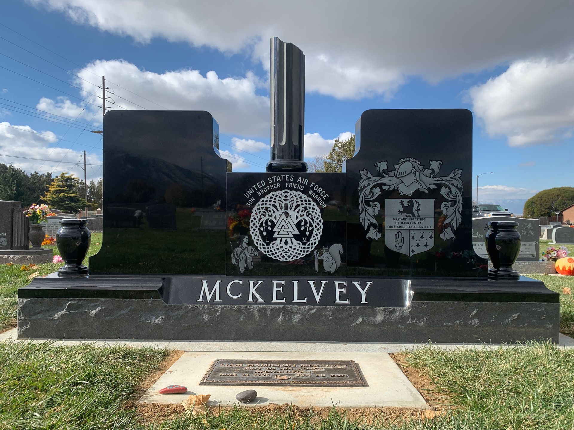 Black granite McKelvey family headstone in a cemetery, with decorative elements and a family crest.