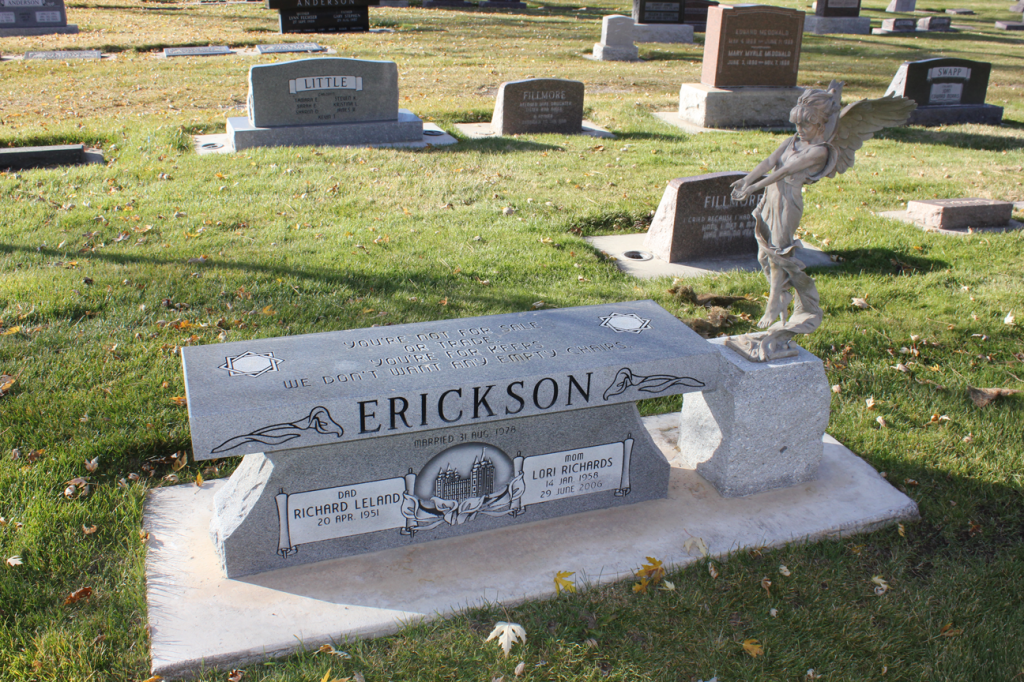 Grave marker with the name ERICKSON, angel statue, and a bench-like design in a cemetery.