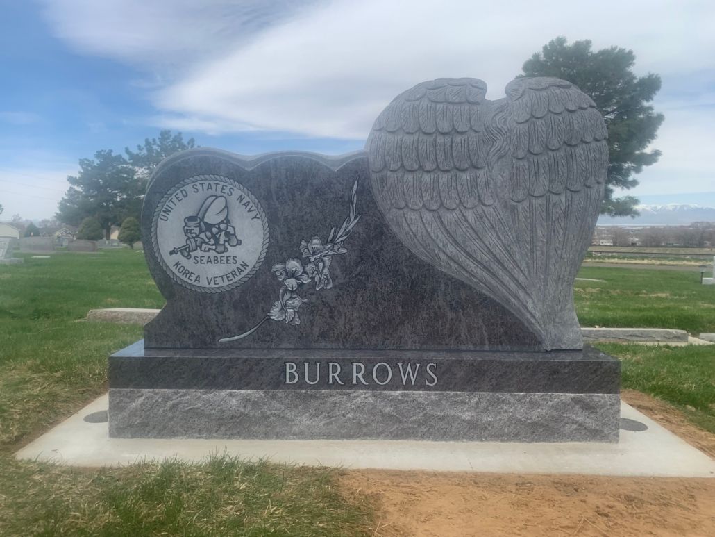 Granite headstone with angel wing and floral details, BURROWS inscribed.