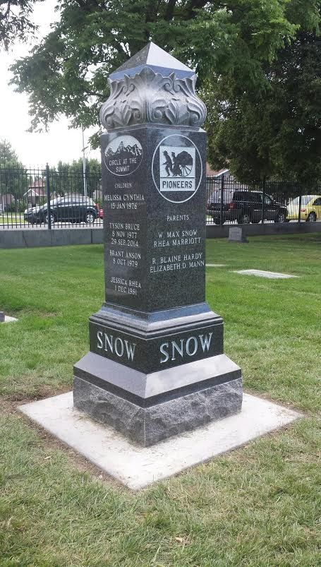 A black stone monument with carved text, in a grassy park.