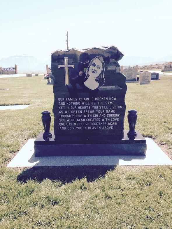 Tombstone with engraved portrait and cross, inscribed with a poem in a cemetery.