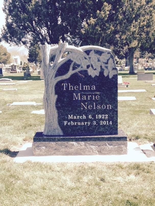 Grave marker for Thelma Marie Nelson: Black stone with tree carving, dates March 6, 1922 - February 3, 2014.