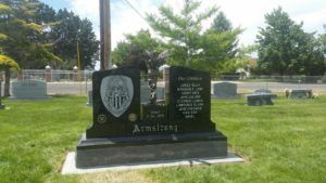 Gravestone of the Armstrong family at a cemetery; black stone with a shield design.