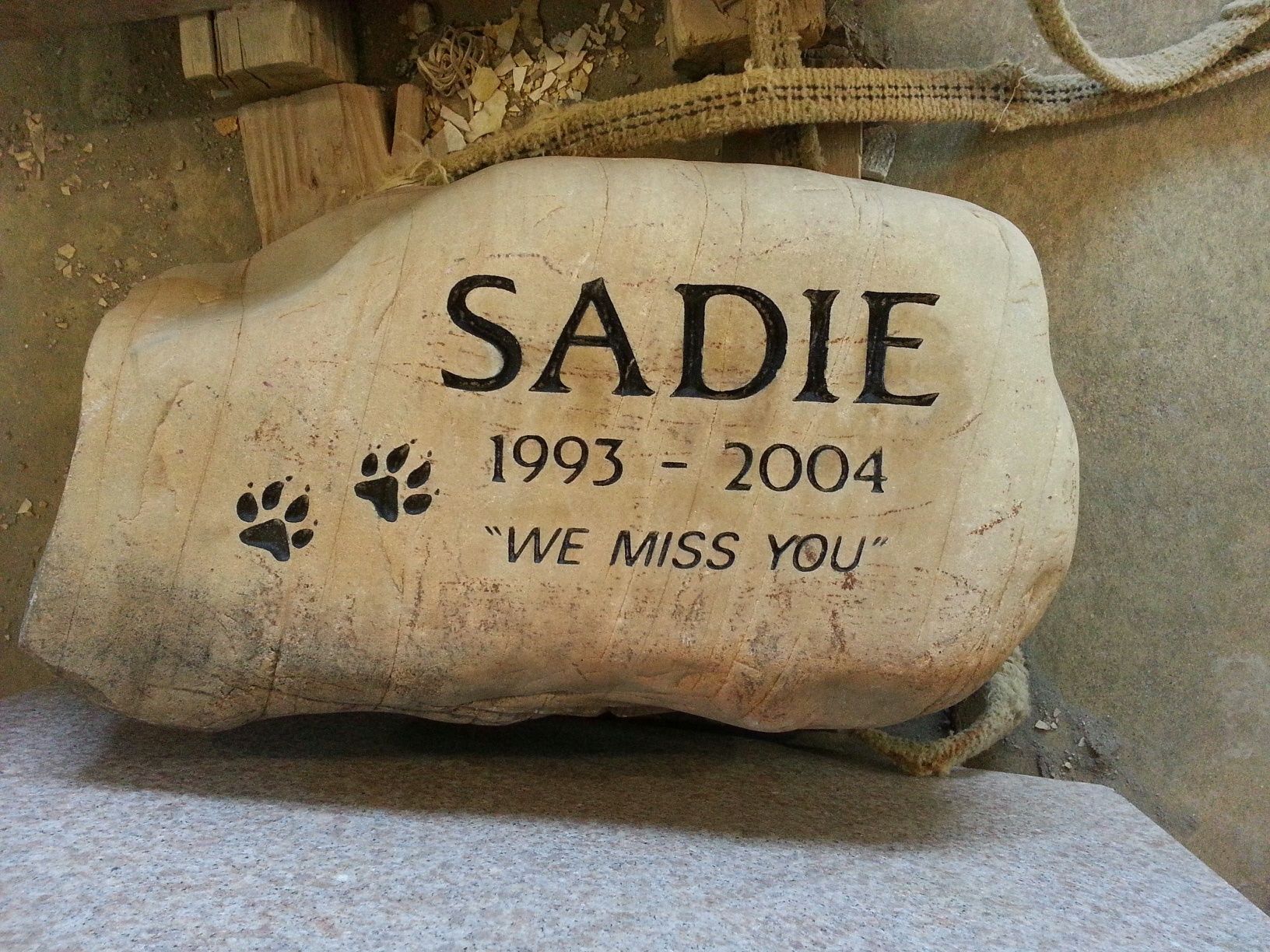 A memorial stone for a pet dog named Sadie: includes name, dates, paw prints, and a message.