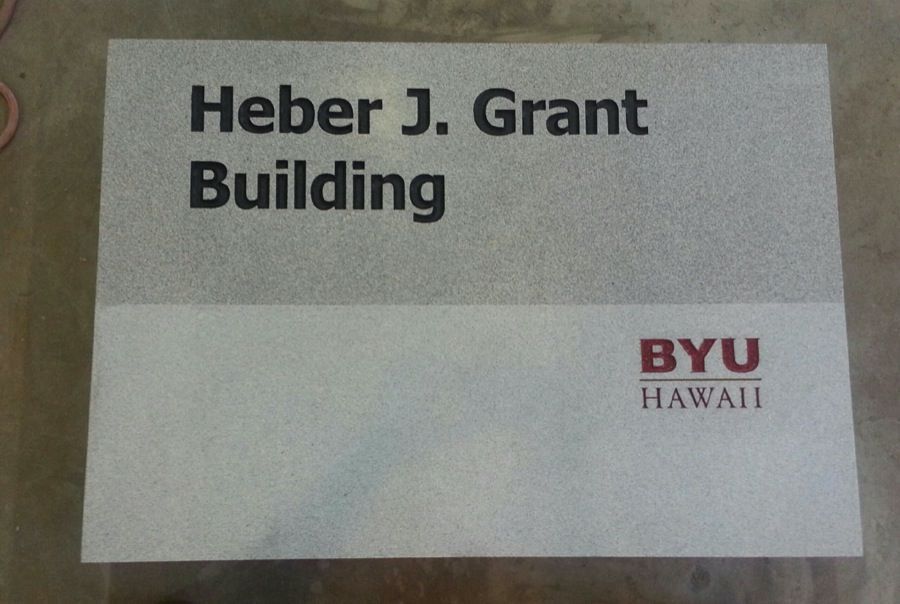 Sign for Heber J. Grant Building at BYU-Hawaii; gray and white with black text and BYU-Hawaii logo.