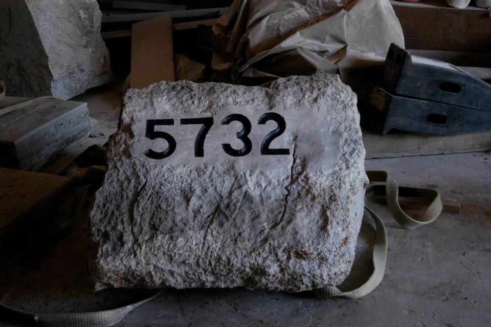 Stone block with the number 5732 painted in black. It is in a cluttered workshop.