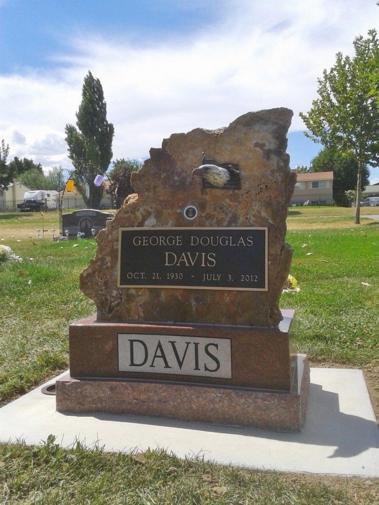 Headstone for George Douglas Davis in a cemetery, brown stone with a bronze plaque, sunny day.