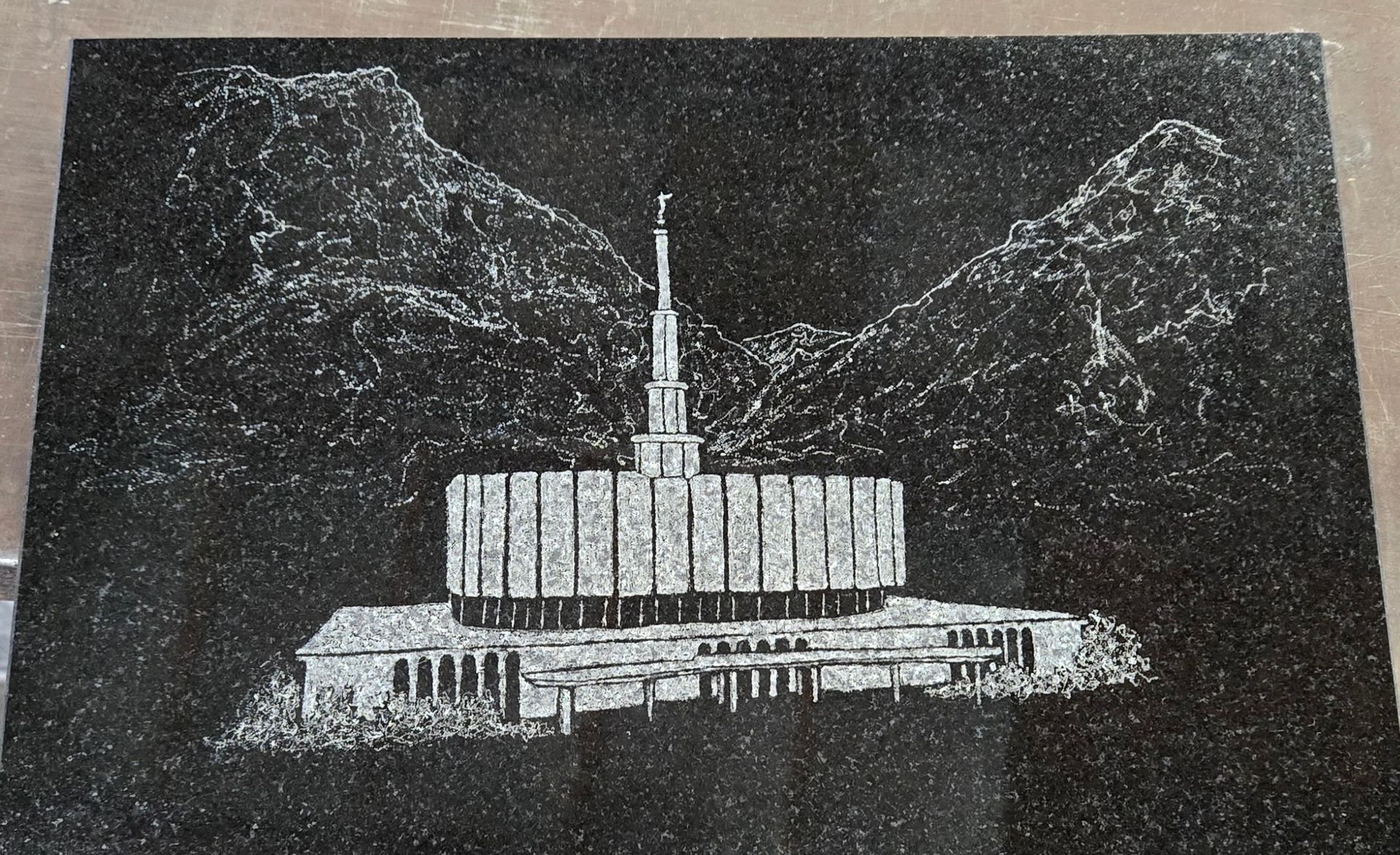 Engraved black granite with temple and mountains.