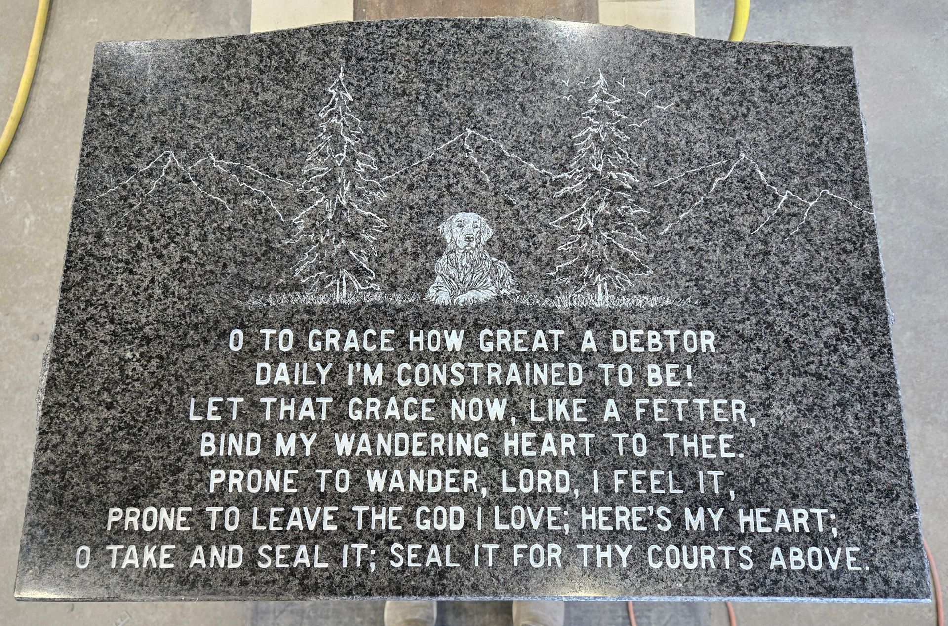 Black granite headstone with engraved hymn, image of a dog, and trees.