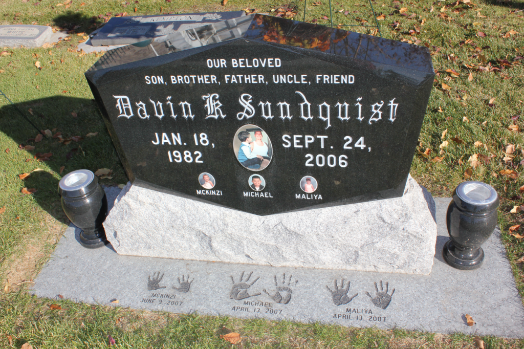Black granite tombstone of Davin E. Sundquist (1982-2006). Includes a photo, handprints, and vases.